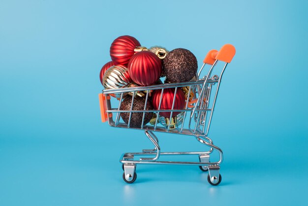 Close up profile photo of small metal with wheels shop cart with pile of gift toy ball presents isolated over blue color bright background