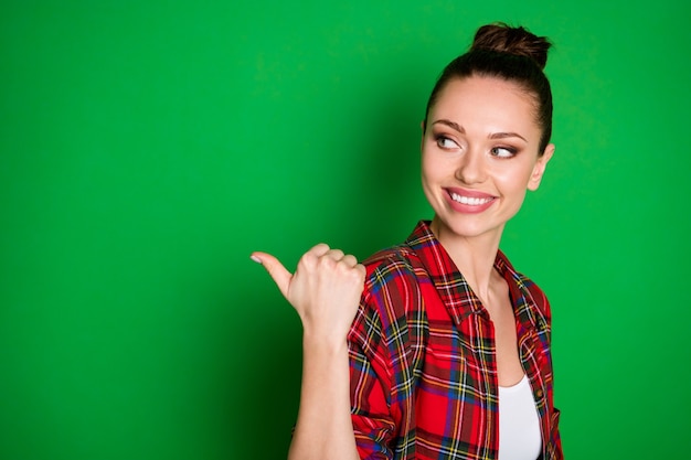 Close-up profile side view portrait of nice-looking attractive charming cheerful girl in checked shirt demonstrating copy space advert isolated on bright vivid shine vibrant green color background