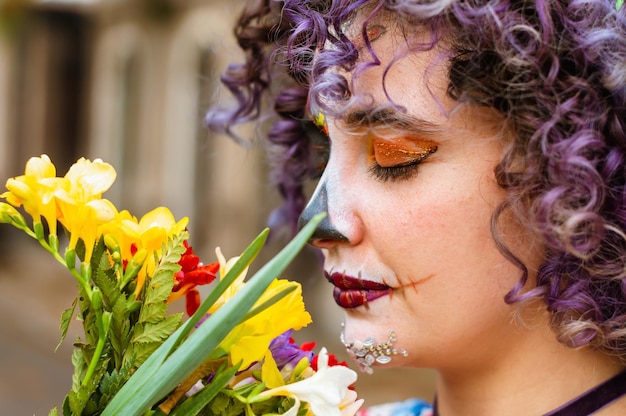 Close up of profile of young latin caucasian woman outdoors smelling flowers