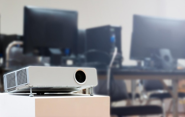 Close up projector with computer desktop on table background in\
computer classroom