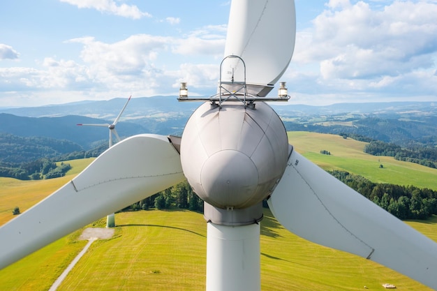 Close up a propeller of the windmill in the yellow field with mountains on the background