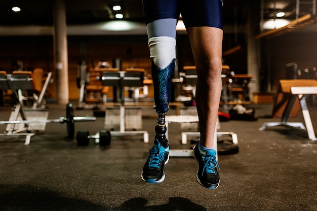 Photo close up of prosthesis leg of young man training in the gym. disabled sportsman concept.