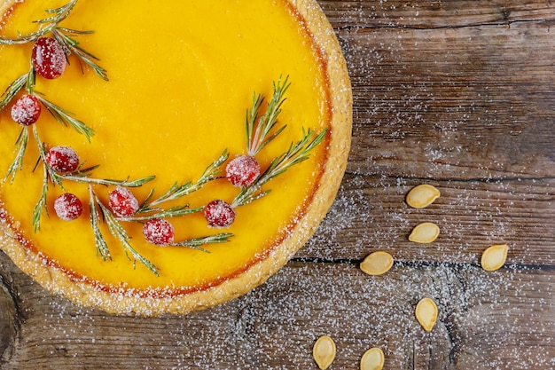 Close up of pumpkin pie with cranberry on rustic background, top view.