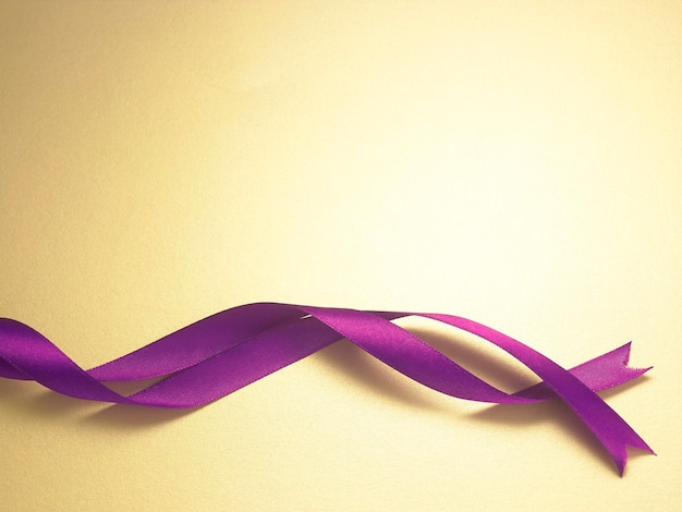 Photo close-up of purple ribbon over yellow background