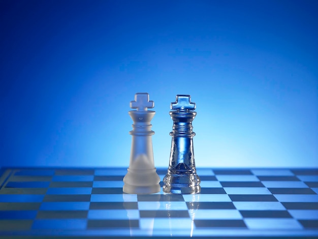 Close-up of queen on chess board against blue background