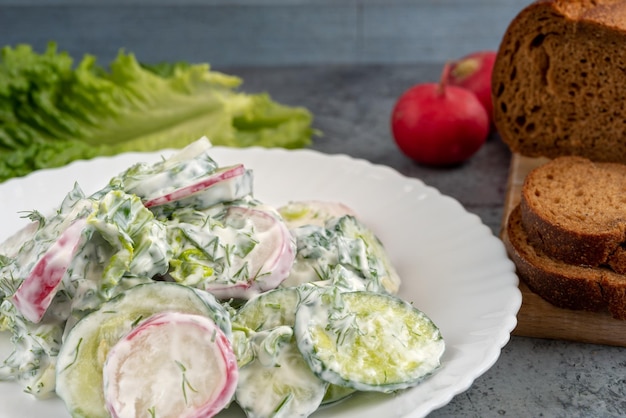 Фото Закройте редисовый и огурцовый салат с кислой сливкой или йогуртным соусом