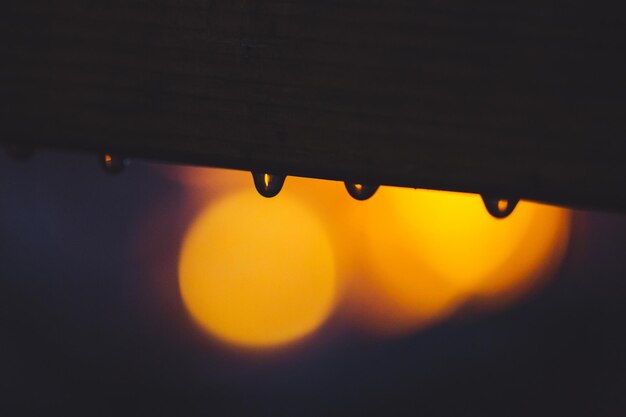 Close-up of rain drops against illuminated lighting equipment