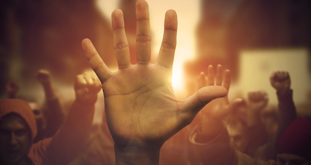 Close-up of raised arm on public demonstration. Group of multi-ethnic protesters on the road with their arms raised up in the air. Multi-ethnic people protesting and fighting for rights.