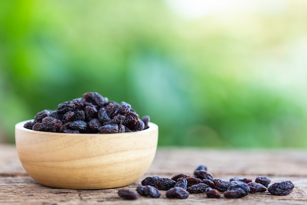 Close up raisins in bowl on wooden table background