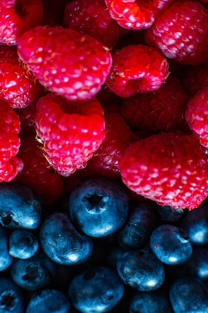 A close-up of raspberries and black blueberry split the frame. Summer vitamins