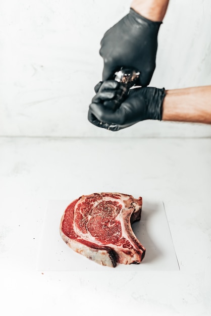 Close-up of raw fresh meat cut for steaks sprinkled with pepper.