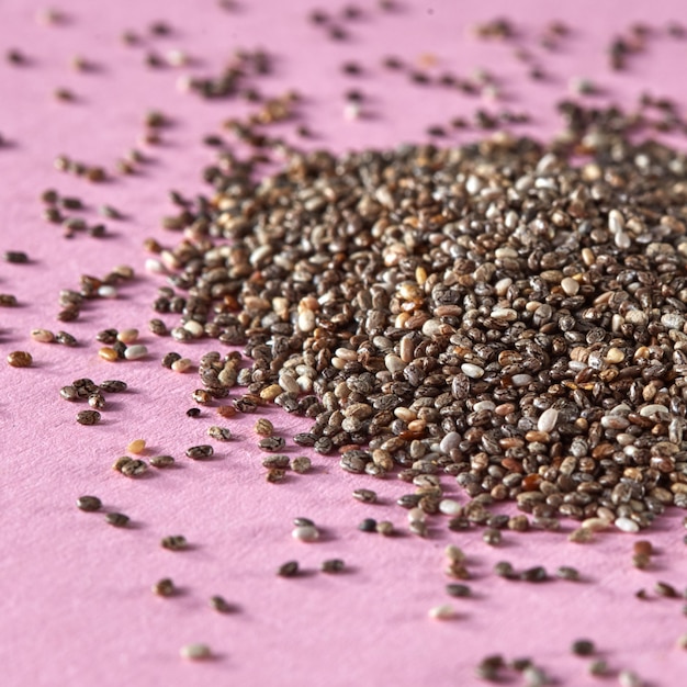 Close up of raw linen seeds in the heap on a pink background. Concept of healthy vegan superfood.