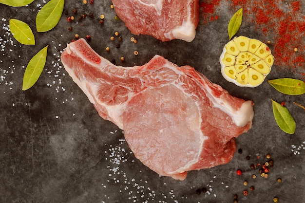 Close up of raw pork chops rib with spices on gray background. Top view.