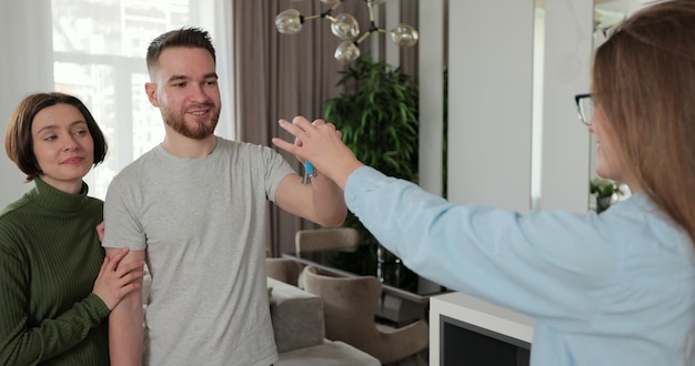 Close up of real estate agent is giving keys to buyers of new apartment Young couple client rent investment Buying home concept