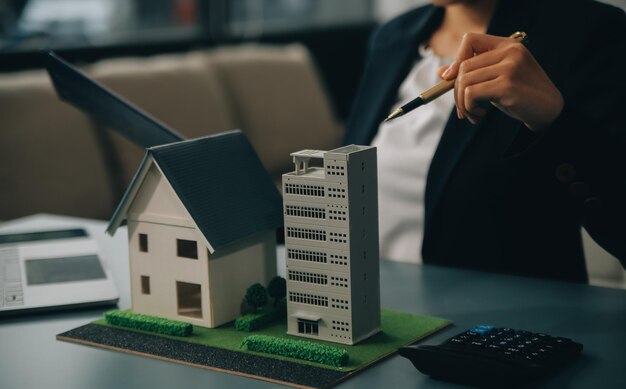 Close up realtor sit at table holds tiny house model layout of cottage Real estate purchase new property ownership construction company make special offer to client affordable dwelling concept