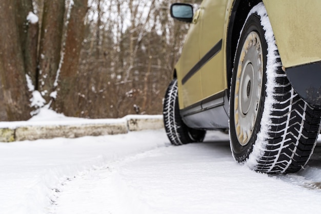 Close up rear view of a family car on parking. Dirty rear wheel tire on snow. Stock photo.