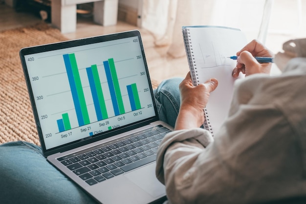 Primo piano vista posteriore giovane donna che utilizza laptop e calcolatrice lavorando su progetto controllando documenti finanziari seduto a tavola a casa guardando lo schermo del computer con diagrammi calcolo fatturexa