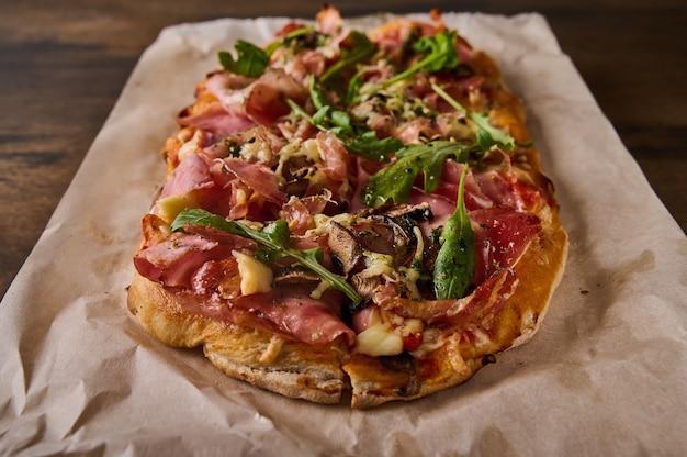 Close-up rechthoekige romeinse pizza met prosciutto ham tomaten mozzarella champignons en rucola