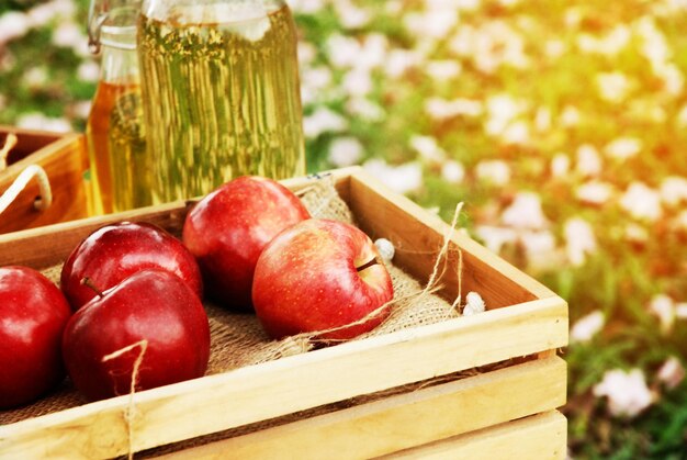 Close-up red apple and apple oil on wood table