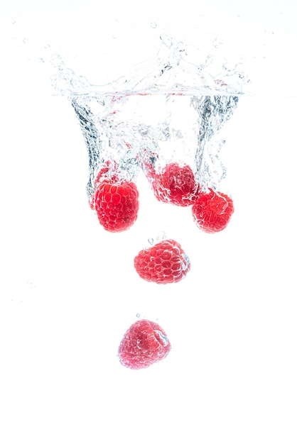 Foto close-up di bacche rosse sull'acqua contro uno sfondo bianco