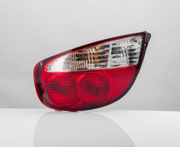 Close up of a red car taillight on a light background with reflection. isolated
