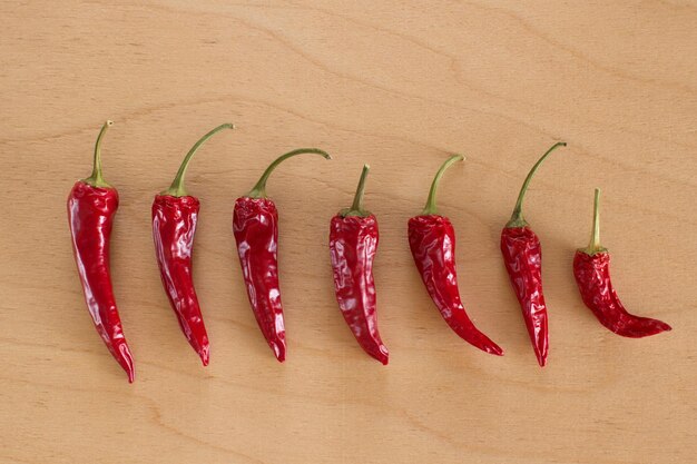 Photo close-up of red chili peppers in row on wooden table