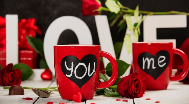 Close-up of red cups and roses on table