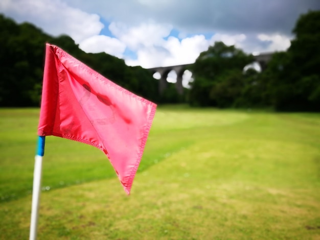 Foto close-up della bandiera rossa sul campo da golf contro il cielo