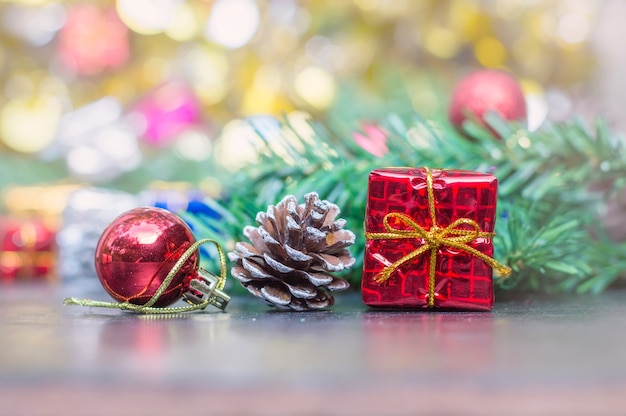 Close up of red gift box, pine cone, red ball on wooden table for Christmas 