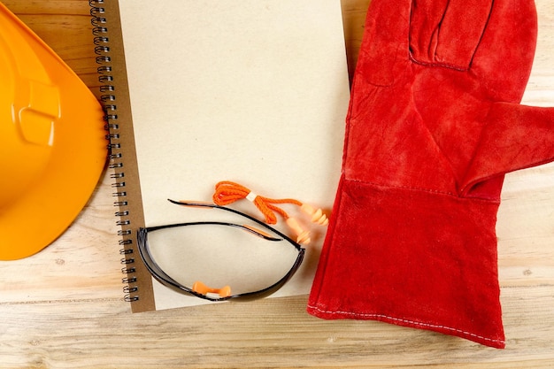 Close-up of red glove by book and hardhat on table