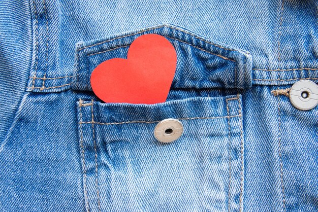 Foto close up di un cuore rosso che si vede dalla tasca di una giacca di jeans