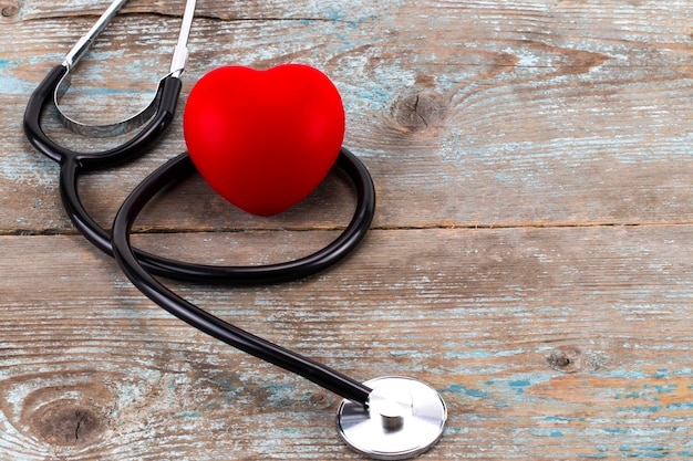 Foto primo piano cuore rosso e stetoscopio su tavola di legno, concetto di giornata mondiale della salute, tono vintage di processo.