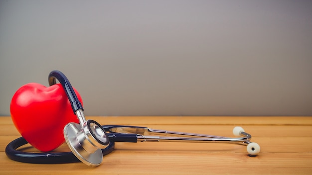 Close up red heart and steythoscope on old wood table 