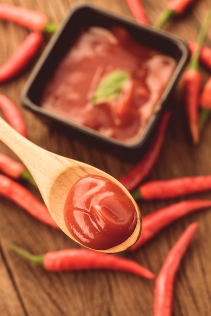 Close up of red hot chilli sauce in wood spoon