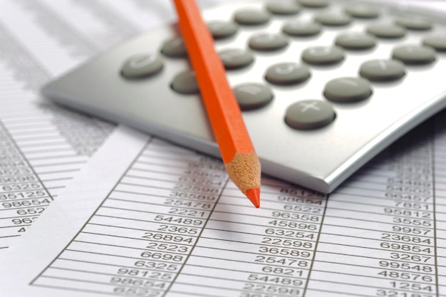 Photo close-up of red pencil with calculator and documents on table