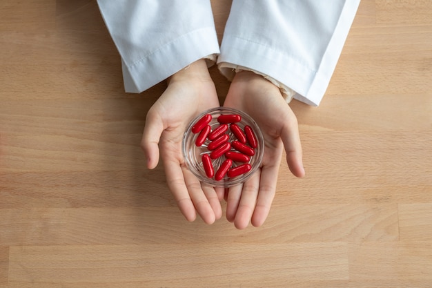 Close-up of red pill in the woman's hand.