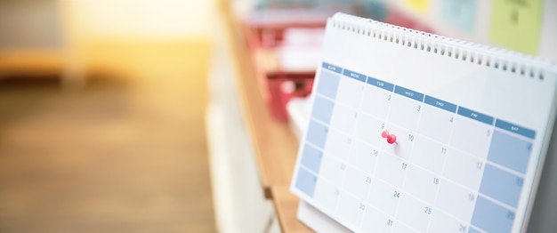 Foto primo piano un perno rosso sul calendario da tavolo vuoto.