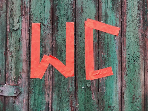 Foto close-up del cartello rosso del bagno sulla vecchia porta di legno