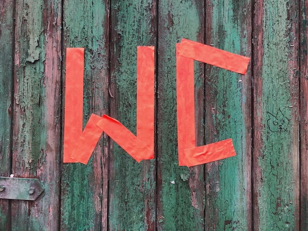 Close-up of red restroom sign on old wooden door