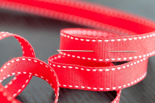 Close-up of red ribbon and sewing needle on table