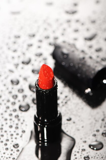 Close up of red saturated lipstick with water drops.