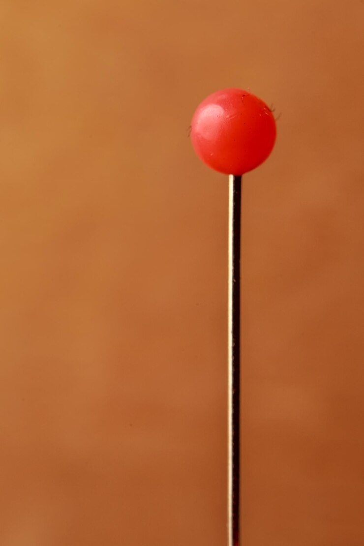 फोटो close-up of red straight pin against brown wall