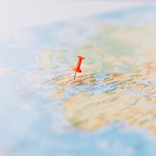 Close-up of a red thumb tack on defocused world map