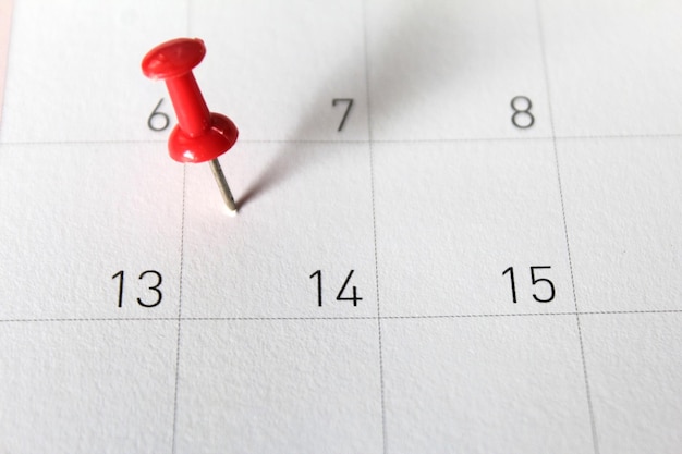 Photo close-up of red thumbtack on calendar