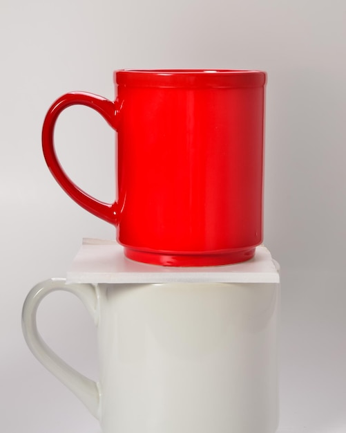 Close-up of red and white coffee cups against white background