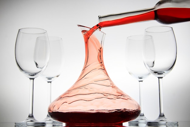 Photo close-up of red wine pouring in jar against white background