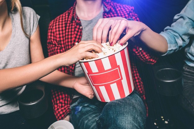 Close up of red with white basket of popcorn that both girl and guy are holding