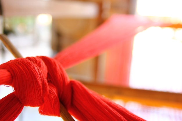 Close up red yarns on wood loom weaving ready to produce.