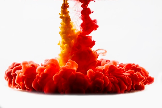 Photo close-up of red and yellow ink dissolving underwater against white background