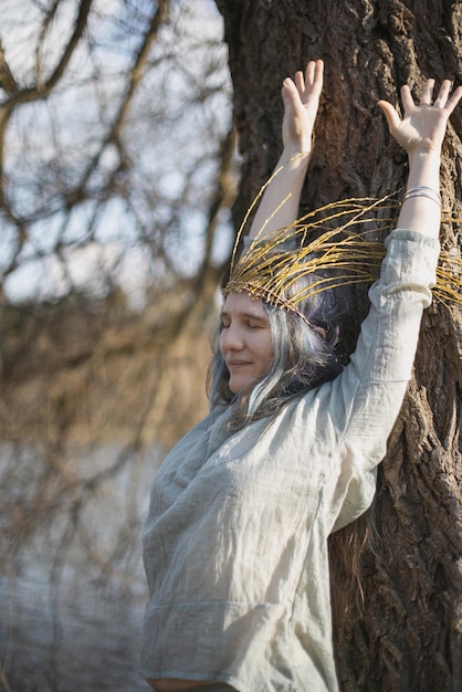 Close up relieved woman with willow crown stretching arms up\
portrait picture